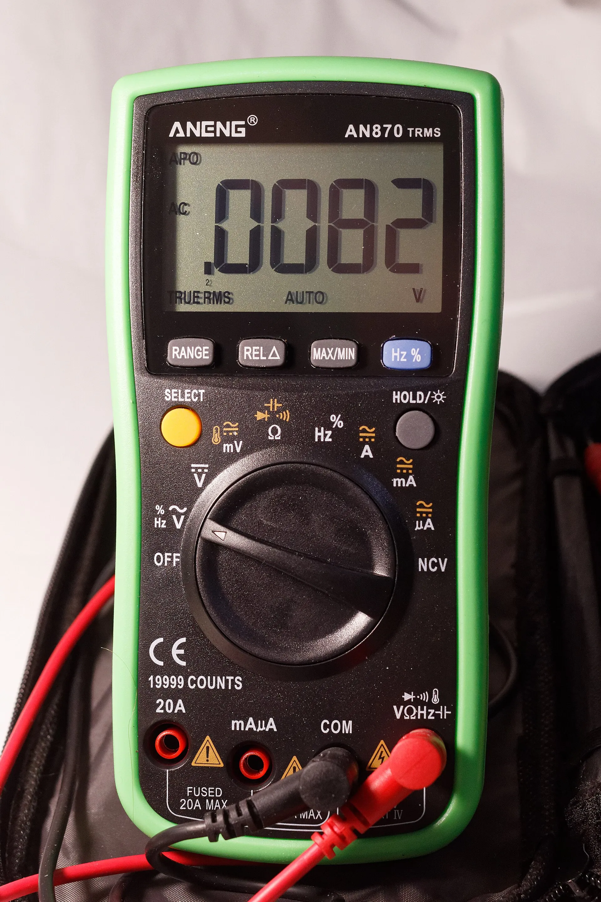 Multimetro digitale verde e nero con display, selettore rotativo delle portate, quattro boccole in basso e due puntali, uno rosso e uno nero.